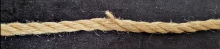 Close-up of jute rope showing broken and separated fibers.