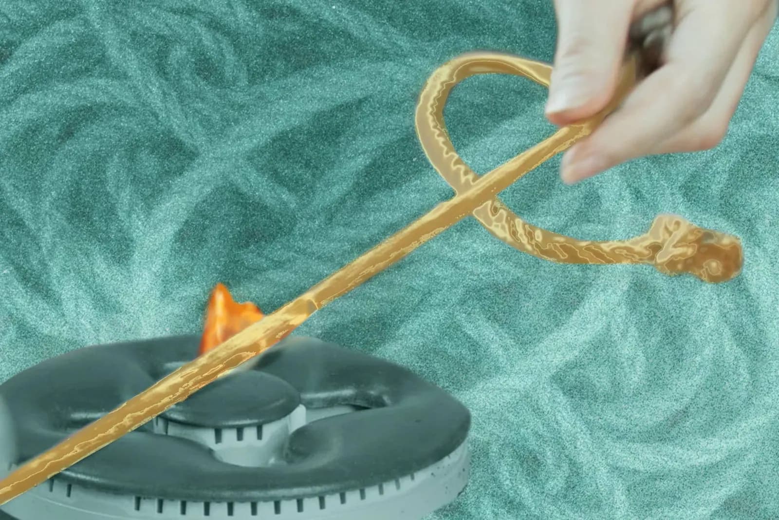 Hand holding jute rope burning off fuzzies over a gas burner with a teal rope background.