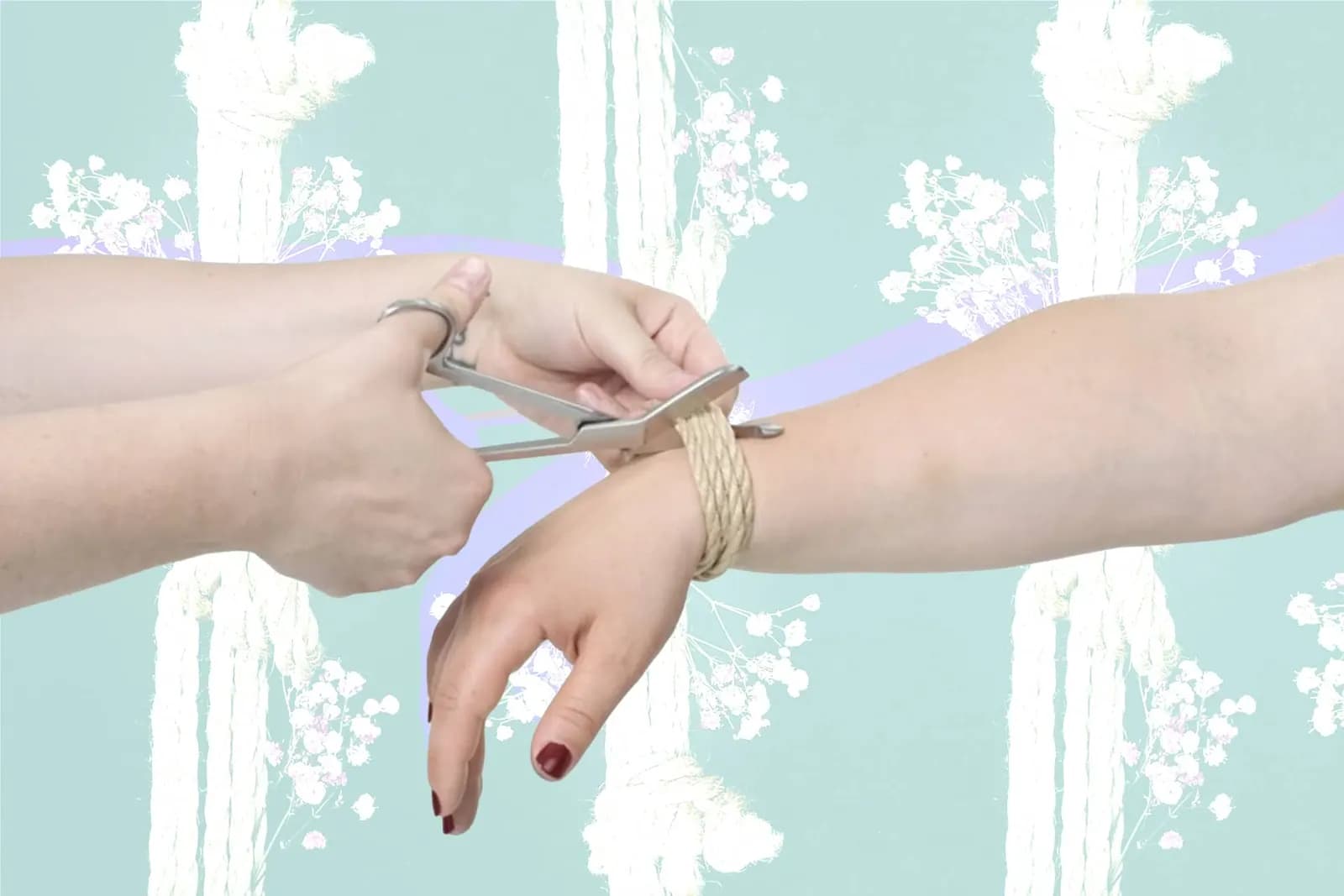 shibari rope cut with safety shears on wrist-bound hand, pastel floral rope background.