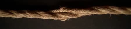 A length of jute rope with uneven fiber damage and twisted sections.