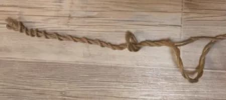 Rope laid on wood showing multiple twisted sections and areas of fiber loss.