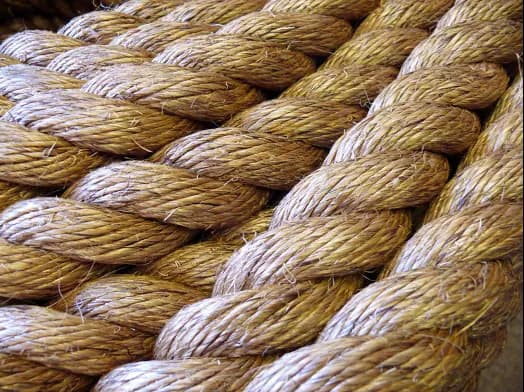 A close-up of twisted natural jute shibari rope showing rope structure and texture.