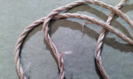 Pink jute rope showing multiple areas of fiber separation and wear.