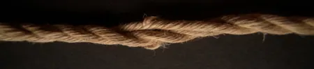 A length of jute rope with uneven fiber damage and twisted sections.