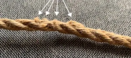 Jute rope on gray fabric with visible fraying and fiber separation throughout.