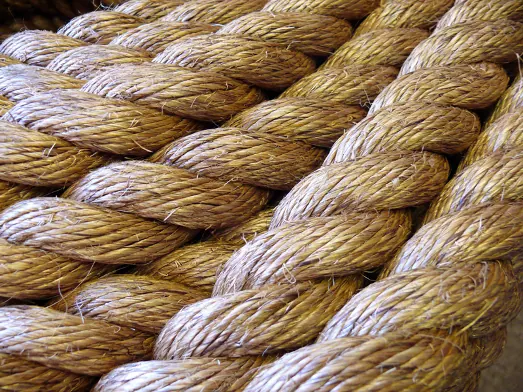 A close-up of twisted natural jute shibari rope showing rope structure and texture.